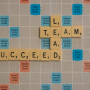 scrabble board: "Lead Team Succeed"